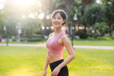 Mutlu bir Asyalı kadın olarak yaşamanın mutluluğunu yaşayın. 30 'lu yaşlarda, gün batımında parkta gülümseyen bir gülümsemeyle kameraya bakın. Refah kavramını benimse..