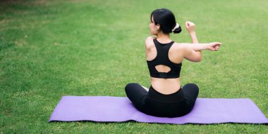 Portre, yoga minderli pembe spor giysili genç Asyalı kadına uyuyor. Parkta kasları germek. Kendinizi doğanın iyileştirme enerjisine alıştırın. İyiliği yükselt ve ruhunu tazele..