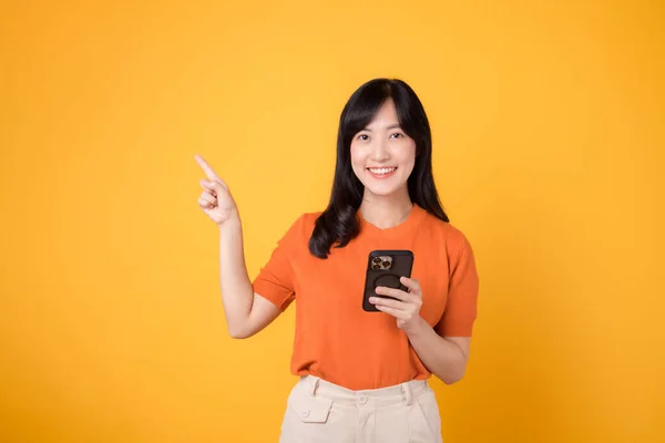 Szczęśliwa Młoda Azjatka Trzydziestce Pomarańczowej Koszuli Pomocą Smartfona Wskazując Wolne — Zdjęcie stockowe
