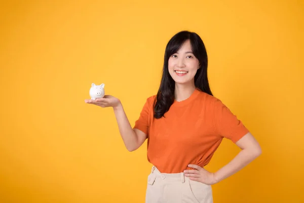 Mulher Asiática Radiante Segurando Banco Porquinho Mãos Quadris Fundo Amarelo — Fotografia de Stock