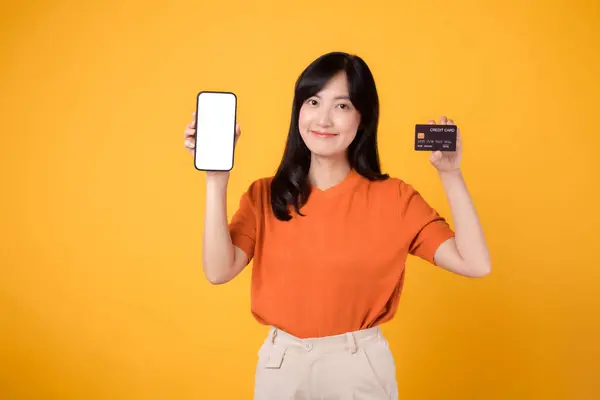 Dynamiczna Azjatka Trzydziestce Prezentująca Smartfona Kartę Kredytową Żółtym Tle Łatwe — Zdjęcie stockowe