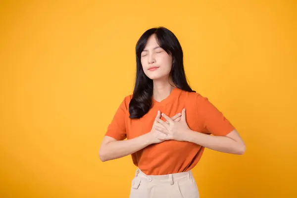 Empathische Aziatische Vrouw Draagt Een Oranje Shirt Houdt Handen Borst — Stockfoto