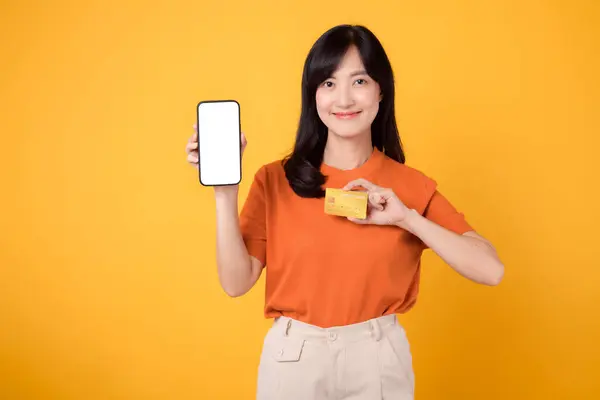 Улыбающаяся Летняя Азиатка Оранжевой Рубашке Используя Смартфон Указывает Свободное Пространство — стоковое фото