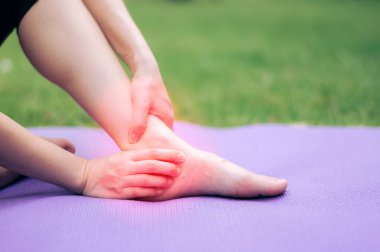 Sporcu kadın, parkta yoga minderinde egzersiz yaptıktan sonra bileğini tutuyor. spor konseptinde yaralanma kazası.