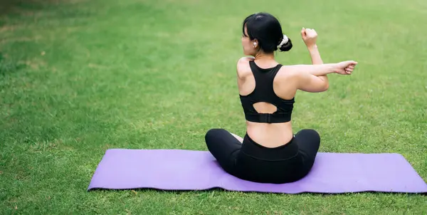 portrait fit young Asian woman in pink sportswear with yoga mat. stretching muscles in park. Experience power of yoga in nature. A young woman\'s practice embodies balance and serenity.
