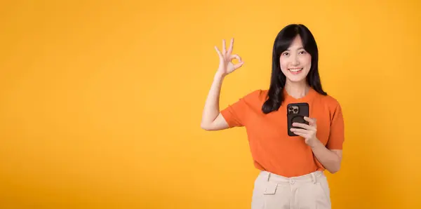 Energetische Junge Asiatin Die Orangefarbenem Hemd Smartphone Mit Handzeichen Auf — Stockfoto