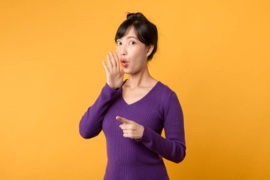 Vay canına. Genç, duygusal olarak şaşırmış, ağzı açık Asyalı bir kadın. Sarı stüdyo arka planında izole edilmiş güzel yarı boy kadın portresi. İnsani duygular, yüz ifadesi kavramı.