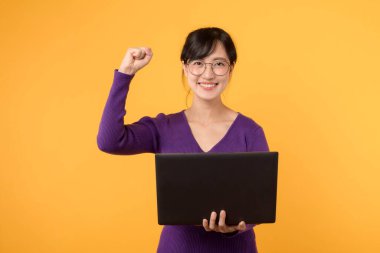 Mor gömlek ve gözlük takmış, mutlu ve kendinden emin genç bir kadın, elinde bir dizüstü bilgisayar tutuyor, sarı bir arka plana karşı teknolojiden anlayan bir profesyoneli temsil ediyor..