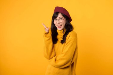 Düşünceli, 30 'larında genç bir kadın, kırmızı bereli ve gözlüklü, güneşli sarı bir arka planda derin düşüncelere dalmış..