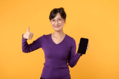 Parlak gülüşlü, mor gömlek ve gözlük takan akıllı telefonunu iletişim ve alışveriş için kullanan güzel bir kadın. Çevrimiçi dünyayı sarı bir zemine bağlamak, ifade etmek ve eğlendirmek