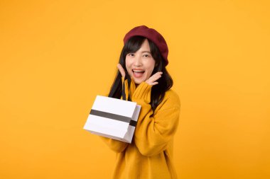 30 'lu yaşlarda, elinde bir alışveriş çantası olan, sarı süveter ve kırmızı bereyle moda anlayışını sergileyen Asyalı bir kadın..