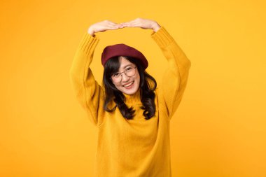 Aşkını bir kalp hareketiyle ifade et. Sarı kazaklı, kırmızı bereli ve gözlüklü şık 30 'lu yaşlarda bir kadın..