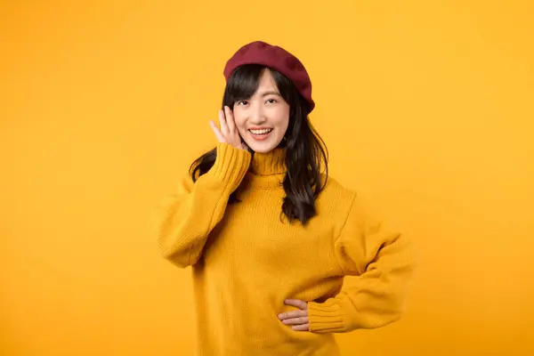 年轻的亚洲女人30多岁 热情地做着一个时髦的宣布 穿着一件黄色毛衣和红色贝雷帽 衬托在生机勃勃的黄色背景上 — 图库照片