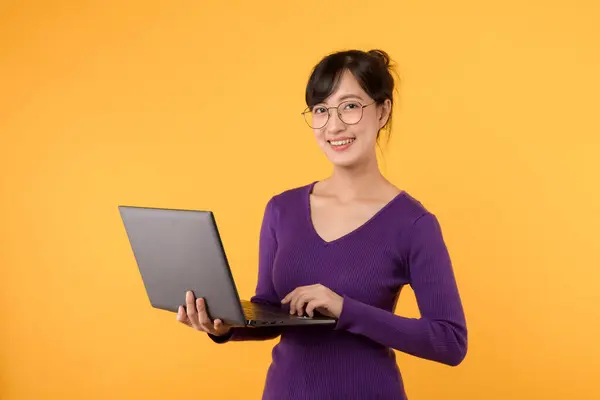 노란색 배경에 노트북을 미소와 보라색 셔츠와 안경을 아시아 비즈니스Woman 로열티 프리 스톡 이미지