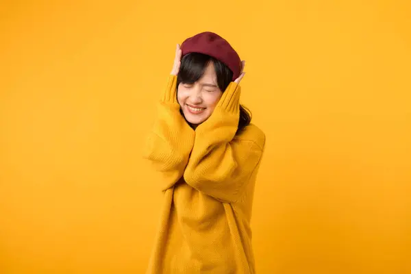 활기찬 아시아 노란색 스웨터와 빨간색 노란색 배경에 그녀의 작곡을 유지하면서 로열티 프리 스톡 사진