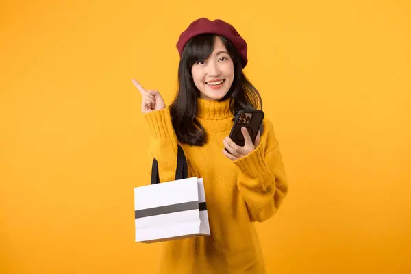 Modebewusste Junge Asiatin Die Mit Einkaufstasche Und Smartphone Der Hand lizenzfreie Stockfotos