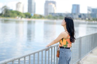 Rıhtımda konuşmanın keyfi, turuncu gömlekli genç bir kadın açık havanın güzelliğinin tadını çıkarıyor..