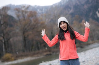 Manzaralı ufuk, pembe postu olan Asyalı kadın karlı bir maceranın keyfini çıkarıyor. Göl kenarındaki zarif portre bir yolculuğun heyecanını ve keşfini yakalıyor..