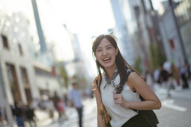 Çantalı bir Japon kadının şehir cazibesinin tadını çıkarın. Yol köşesinde güvenle ayakta duruyor. Asya 'da gündelik hayatın oldukça enstantane bir fotoğrafı..