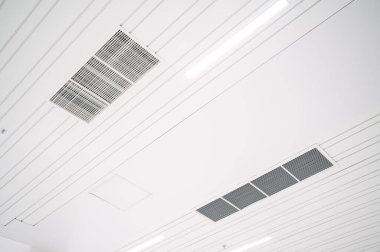 Tavana monte edilmiş kaset tipi klima ve beyaz tavanda modern lamba ışığı. Ofis ya da ev havalandırması
