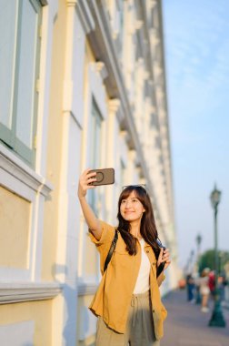 Gezgin Asyalı 30 'lu yaşlarda, Bangkok, Tayland' a seyahatin tadını çıkaran akıllı bir telefonla canlı yayın ve sefie yapıyor. Seyahat yaşam tarzı, dünya turisti ya da Asya yaz turizmi konsepti.