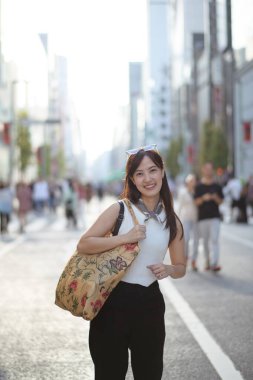 Japon sokak titreşimleri, bir yol köşesinde kendine güvenen genç bir Asyalı kadın, şık bir çanta onun günlük ve modaya uygun şehir hayatına renk katıyor..