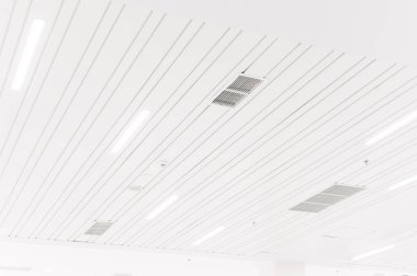 Tavana monte edilmiş kaset tipi klima ve beyaz tavanda modern lamba ışığı. Ofis ya da ev havalandırması