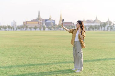 Gezgin Asyalı 30 'lu yaşlardaki kadın Wat Phra Kaew zümrüt Buda' yı keşfederken akıllı telefondan canlı yayın yapıyor. Yolculuğu boyunca Tayland mirasının mucizelerini paylaş..