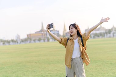 Gezgin Asyalı 30 'lu yaşlarda Wat Phra Kaew zümrüt Buda' yı keşfederken akıllı telefondan canlı yayın ya da selfie çekiyor. Yolculuğu boyunca Tayland mirasının mucizelerini paylaş..