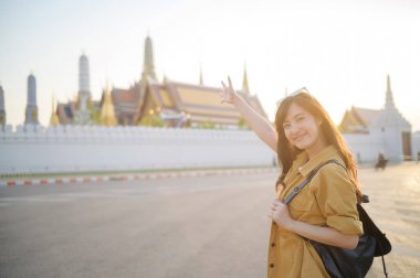 Gezgin Asyalı 30 'lu yaşlarda, sırtında bir sırt çantası, Wat Pra Kaew' in karmaşık detaylarını çocuksu bir merakla araştırıyor. Altın çatılarda gün ışığı dans eder.