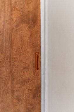 Işık duvarına dayanan parlak saplı, modern tasarım sergilenen tahta bir kapı.