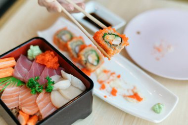 Suşi tabağı, sashimi ve ahşap masada rulo.