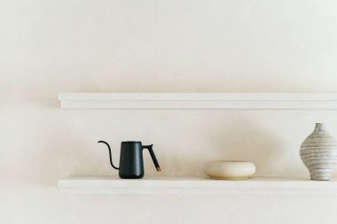 Minimalist siyah çaydanlık ve beyaz raflarda seramik vazo