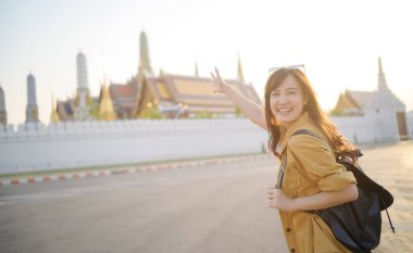 Gezgin Asyalı 30 'lu yaşlarda, sırtında bir sırt çantası, Wat Pra Kaew' in karmaşık detaylarını çocuksu bir merakla araştırıyor. Altın çatılarda gün ışığı dans eder.