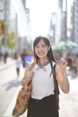 Canlı Tokyo sahnesi, modern Asyalı kadın şehir ışıklarının ortasında güvenle yürüyor..