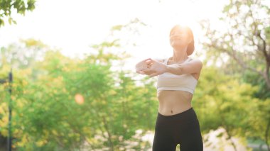 Kadın koşucu. Spor giyim kuşağı olan sağlıklı bir Asyalı kadın koşup dışarıda eğlenmeden önce parkta kaslarını esnetiyor. Kamu parkındaki spor koşucusu kız. Refah konsept demek.