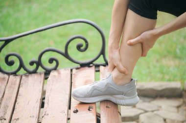 Bileği burkulmuş. Kadın koşucu. 30 'lu yaşlardaki Asyalı kadın spor giysisi giymiş parkta koştuktan sonra bileğini acıdan tutuyor..