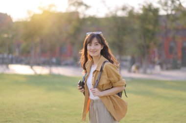 Gezgin Asyalı 30 'lu yaşlardaki kadın gün batımının altın parıltısıyla yıkanmış, keşif özgürlüğünü kucaklıyor. Tatil tatili gezisinde Bangkok, Tayland