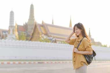 Gezgin Asyalı 30 'lu yaşlarda, sırtında bir sırt çantası, Wat Pra Kaew' in karmaşık detaylarını çocuksu bir merakla araştırıyor. Altın çatılarda gün ışığı dans eder.