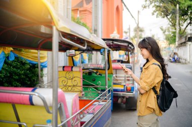 Yaz tatilinde Tuk Tuk taksisinin yanında duran Asyalı genç bayan sırt çantası gezgini. Bangkok, Tayland 'da. Seyahat yaşam tarzı, Asya yaz turizmi konsepti.