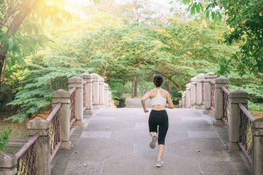 Halk parkında köprüden koşarak geçen Asyalı kadın koşucu..