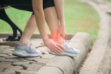 Bileği burkulmuş. Kadın koşucu. 30 'lu yaşlardaki Asyalı kadın spor giysisi giymiş parkta koştuktan sonra bileğini acıdan tutuyor..