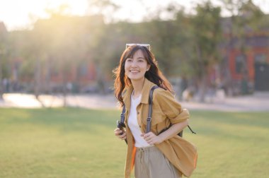 Gezgin Asyalı 30 'lu yaşlardaki kadın gün batımının altın parıltısıyla yıkanmış, keşif özgürlüğünü kucaklıyor. Tatil tatili gezisinde Bangkok, Tayland