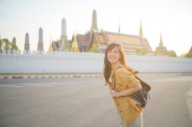 Gezgin Asyalı 30 'lu yaşlarda, sırtında bir sırt çantası, Wat Pra Kaew' in karmaşık detaylarını çocuksu bir merakla araştırıyor. Altın çatılarda gün ışığı dans eder.