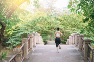 Halk parkında köprüden koşarak geçen Asyalı kadın koşucu..