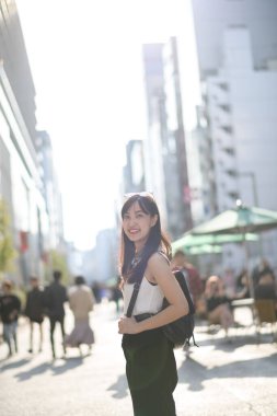 Tokyo 'daki şehir atmosferi, beyaz gömlekli gülümseyen kadın, dinamik şehir manzarasına canlılık katıyor..