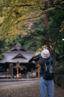 Günlük giysili Asyalı kadın, Japon tapınakları ve tapınaklarının dingin atmosferini, Tokyo ve Kyoto 'daki tatil atmosferleriyle harmanlıyor. Neşeli keşif ve kültürel keşif.