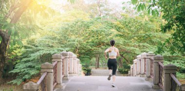 Halk parkında köprüden koşarak geçen Asyalı kadın koşucu..