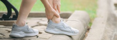 Bileği burkulmuş. Kadın koşucu. 30 'lu yaşlardaki Asyalı kadın spor giysisi giymiş parkta koştuktan sonra bileğini acıdan tutuyor..