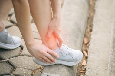 Bileği burkulmuş. Kadın koşucu. 30 'lu yaşlardaki Asyalı kadın spor giysisi giymiş parkta koştuktan sonra bileğini acıdan tutuyor..